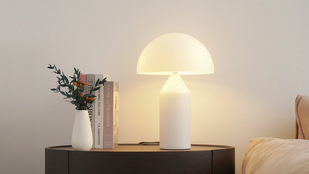 Glowing table lamp beside a vase and books